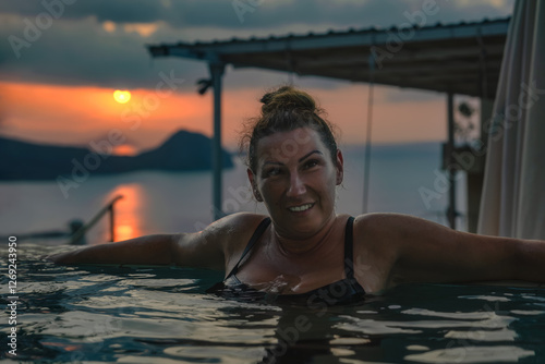 Obraz na płótnie A smiling woman enjoys a moment of relaxation in a tranquil infinity pool, surrounded by a breathtaking sunset that beautifully captures the essence of leisure and outdoor beauty, Komodo, Indonesia w salonie