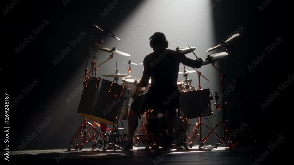 Trap set with hi-hat and bass drums and drummer playing music alone in studio. Professional rock musician rehearsing in night, back view of silhouette of man and drum set in darkness, future rock star