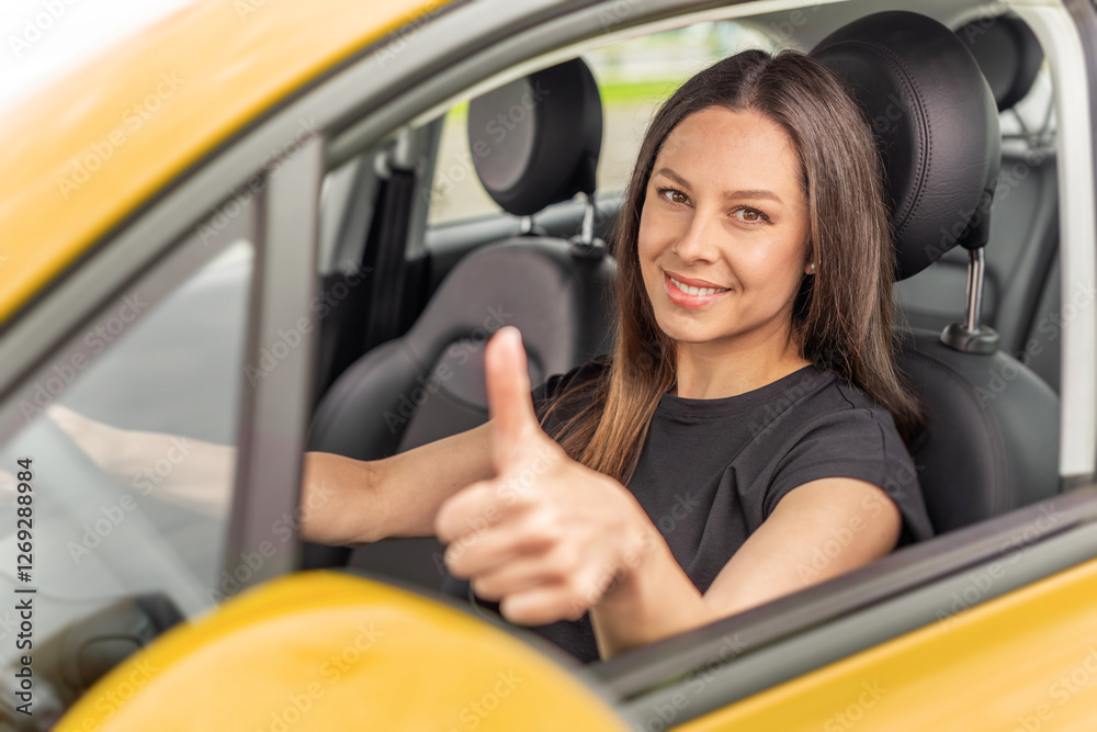 A young woman with long brown hair and a bright smile sits in the driver's seat of a yellow car, giving a thumbs-up gesture through the open window with a confident and positive expression.