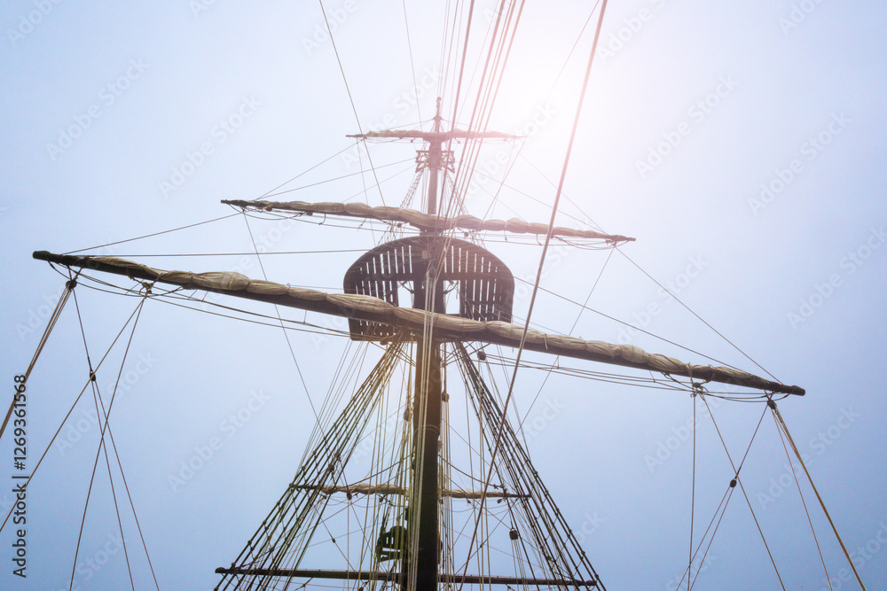 Mast and rigging of the ship silhouetted by bright sunlit sky
