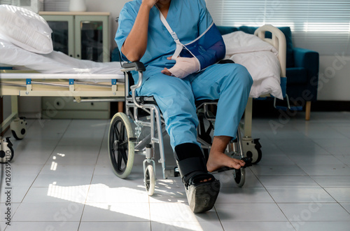 Hospitalized patient recovering in wheelchair, wearing arm sling and ankle brace, focusing on rehabilitation after medical treatment or injury