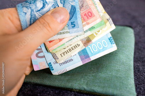 Hand holding Ukrainian hryvnia banknotes over wallet photo