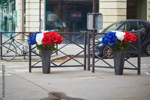 Fototapeta Naklejka Na Ścianę i Meble -  Blue, white and red roses in large vases on a street of Paris, France.