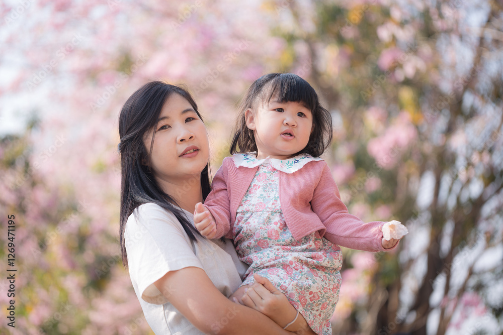 Smiley parent and child,Asian mother and daughter walking in a park with cherry trees. Smiley parent and child,Asian mother and daughter walking in a park with cherry trees.