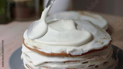 Sweet cream being applied and spread over the sponge cake layer, cake decoration and assembling