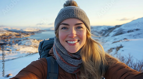 A beautiful, smiling woman with a backpack, standing atop a mountain at sunrise. photo