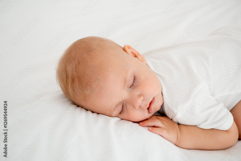 a newborn baby sleeps sweetly on his tummy, a place for text, a baby sleeps on a white bed with a pen under his cheek, a healthy baby's sleep, a close-up portrait a newborn baby sleeps sweetly on his tummy, a place for text, a baby sleeps on a white bed with a pen under his cheek, a healthy baby's sleep, a close-up portrait
