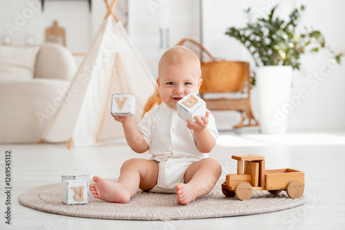 a kid plays with wooden toys, cubes and cars sitting on the floor in a bright children's room, a small child plays and develops, a smiling, joyful baby boy in a white bodysuit