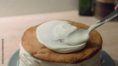 Sweet cream being applied to a cake sponge layer, cake decoration and assembling