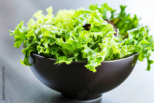 Bowl of green lettuce is on a wooden table. photo