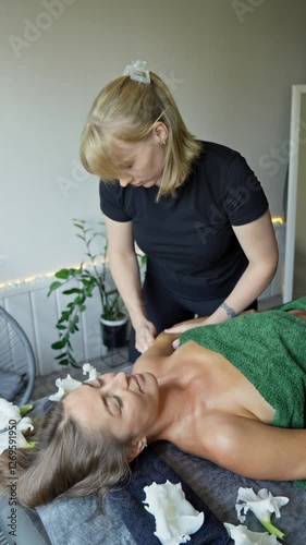 Brunette woman relaxing in beauty salon lying on massage table. Hand of masseuse doing massage. Young woman enjoying relaxing massage at spa. Vertical video. Cinematic in 4K, UHD