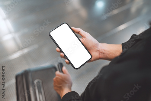 Back view of man using smartphone with white blank screen mockup in airport terminal, Traveler with phone with suitcase, copy space for advertising. photo