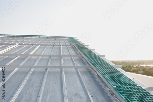 a green fiberglass grating panel installed on a metal framework. The grating panel has a grid-like structure with square openings and is secured to the metal framework with bolts at the corners.