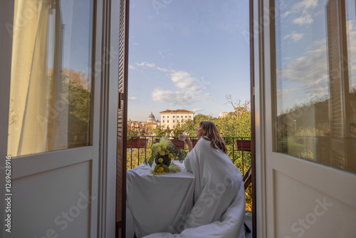 Obraz na płótnie A woman wrapped in a soft white blanket enjoys a peaceful morning on a charming balcony in Rome, overlooking St Peters Basilica w salonie