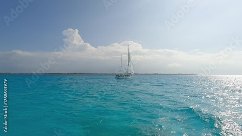 A beautiful sailboat glides over turquoise ocean waters, evoking tranquility