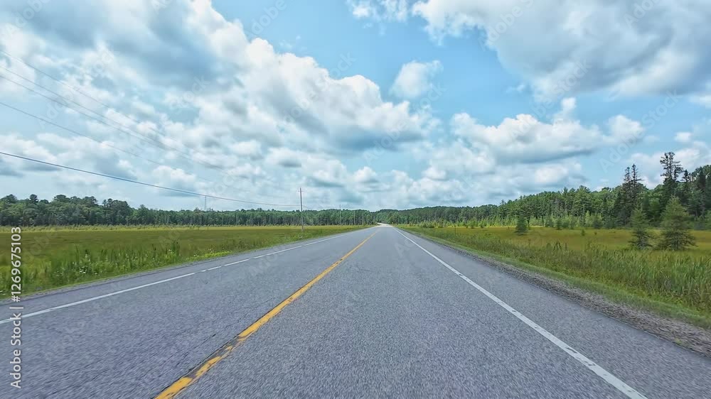 Beautiful summer view of a highway weaving through Canadian forests. Scenic driver POV front plate while travel by camper van. Driving plate road trip along the asphalt road from motorized RV, Canada. Beautiful summer view of a highway weaving through Canadian forests. Scenic driver POV front plate while travel by camper van. Driving plate road trip along the asphalt road from motorized RV, Canada.