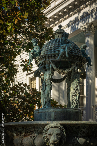Metal Figures atop a Fountain Basin in the private Garden of a expensive Property with Mansion in Background