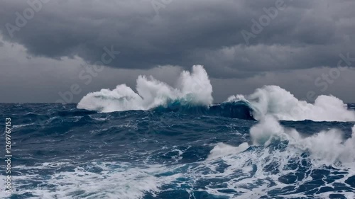 Slow Motion Shot of a Rough Blue Ocean – Powerful Waves Crashing, Deep Blue Water with White Foam, Strong Winds Disturbing the Surface, Dynamic and Intense Motion, Sunlight Reflecting Off the Churning