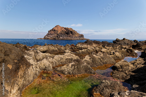 Obraz na płótnie Roque de Garachico islet view from a rocky beach with green sea water in natural coastal pool in Tenerife. Rock islet is a protected area. Nature reserve serves as perfect habitat for birds nesting. w salonie