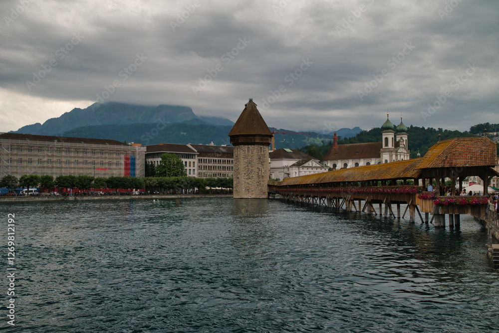Fototapeta premium View of the Kapellbrücke bridge a bridge spanning the Reuss river in the city of Lucerne (Switzerland), during a cloudy day in spring.