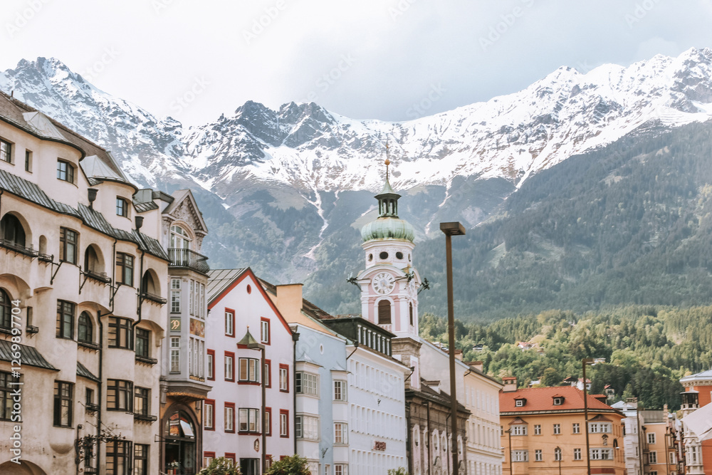 Naklejka premium Stunning view of Innsbruck, Austria, where snow-capped mountains meet colorful architecture in a picturesque alpine setting.