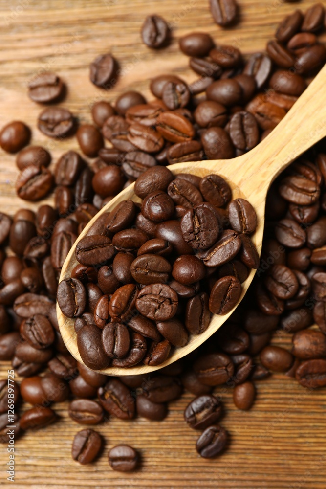 Fresh coffee beans in a wooden spoon on a wooden background Fresh coffee beans in a wooden spoon on a wooden background