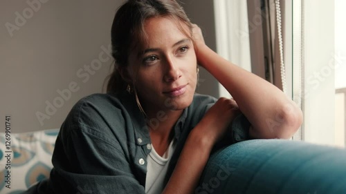 Young woman daydreaming sitting on sofa in living room