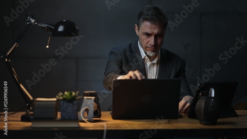 Wallpaper Mural Businessman sitting at desk with laptop computer. Entrepreneur working late in office. Older, middle aged, mid adult, man in his 40s or 50s in jacket, business casual. Torontodigital.ca