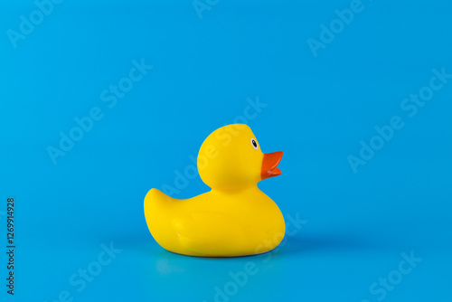 Fotografie Bright Yellow Rubber Duck Against a Vibrant Blue Background: A Playful and Nosta