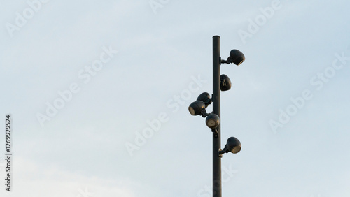 Minimalist View of a Tall Black Street Light Pole with Multiple Spotlights Against a Clear Sky