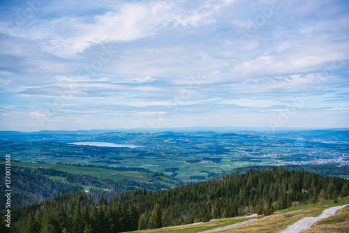 A breathtaking view of the foothills of Mount Pilatus near Lucerne, Switzerland. Green forests, yellow rapeseed fields, and a shimmering lake create a stunning landscape in Central Switzerland.