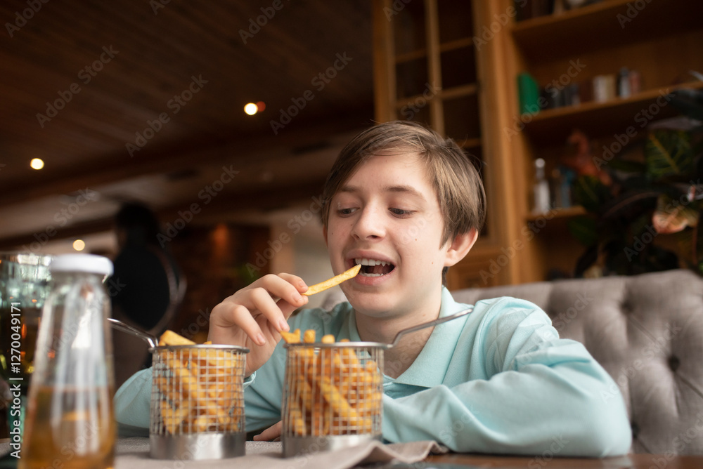 boy eating french fries in a restaurant or cafe boy eating french fries in a restaurant or cafe