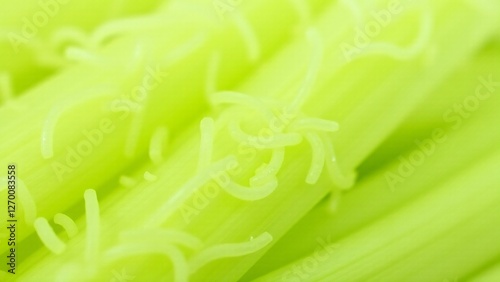 A close-up of celery's fibrous, stringy texture with pale green stalks. Lighting emphasizes its intricate and moist surface.