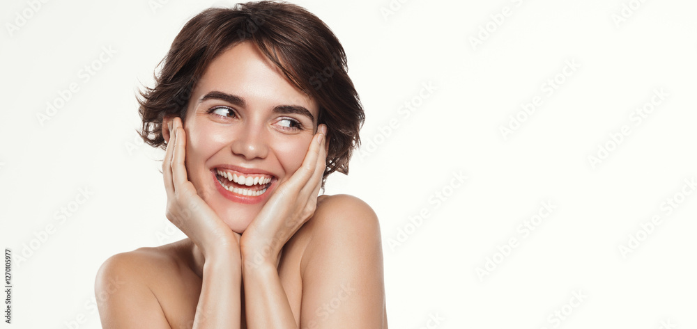 Close up of beautiful, happy woman with short haircut, holds hands on cheeks, looks away at promo banner and smiles, enjoys feeling of soft, nourished skin after peptide treatment, white background Close up of beautiful, happy woman with short haircut, holds hands on cheeks, looks away at promo banner and smiles, enjoys feeling of soft, nourished skin after peptide treatment, white background