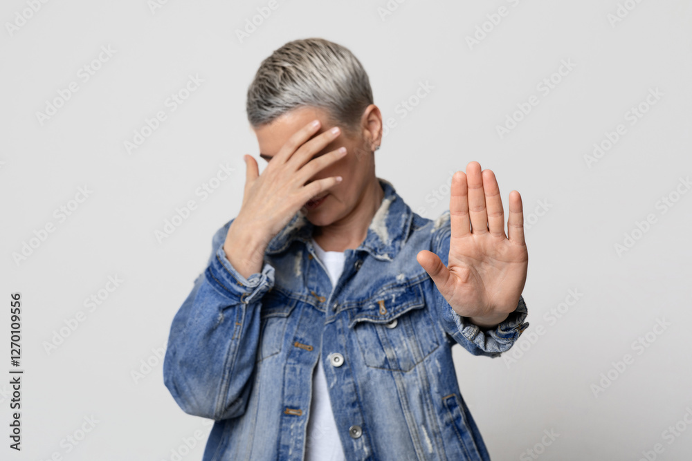 Domestic Violence Victim. Unrecognizable mature woman making stop gesture and covering her face, standing over light studio background, free space Domestic Violence Victim. Unrecognizable mature woman making stop gesture and covering her face, standing over light studio background, free space