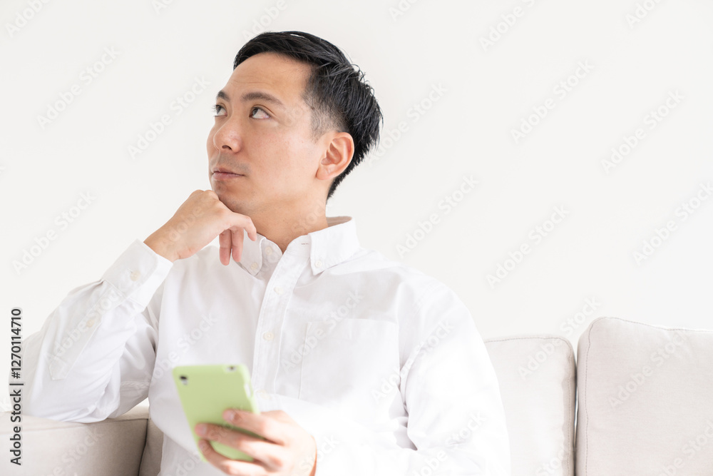 部屋でスマホを見る男性 部屋でスマホを見る男性