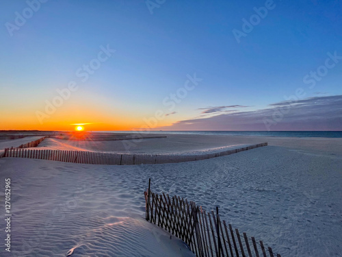 Gorgeous Orange Sunrise on white sand beach with barrier at the front, little cloud in the side  in Long Island NY, USA - concept of nature, 