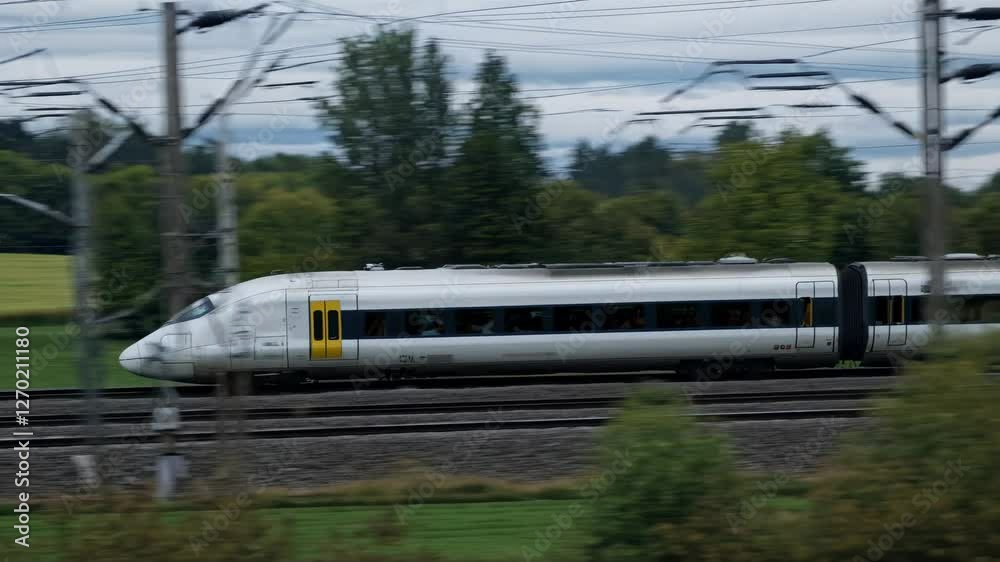 Side view of a high-speed train in motion, captured from a low angle. The video conveys speed and modernity against a blurred natural backdrop.