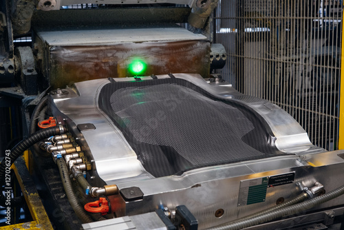 Industrial machinery forming carbon fiber with a bright green laser light showcasing precision and technology