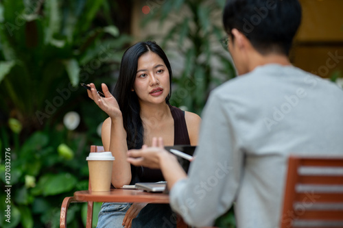 Fotografi A confident Asian woman having an informal meeting with her colleague or client at a cafe