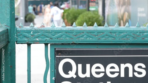 New York subway sign, Queens underground metro station. Metropolitan entrance fence, public transport exit. Long Island city street, NYC United States. Navigation text on signboard. Pedestrians people