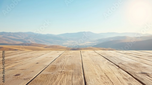 A weathered wooden platform stretches out towards breathtaking mountain views under a clear blue sky. The sunlight casts a warm glow on the natural scenery, inviting relaxation and tranquility
