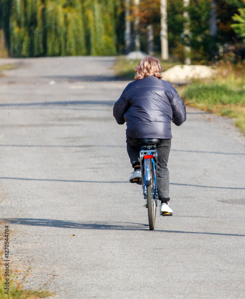 Obraz premium A woman is riding a bicycle down a road