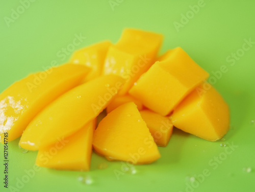 Fresh slices of juicy ripe mango on bright green background photo