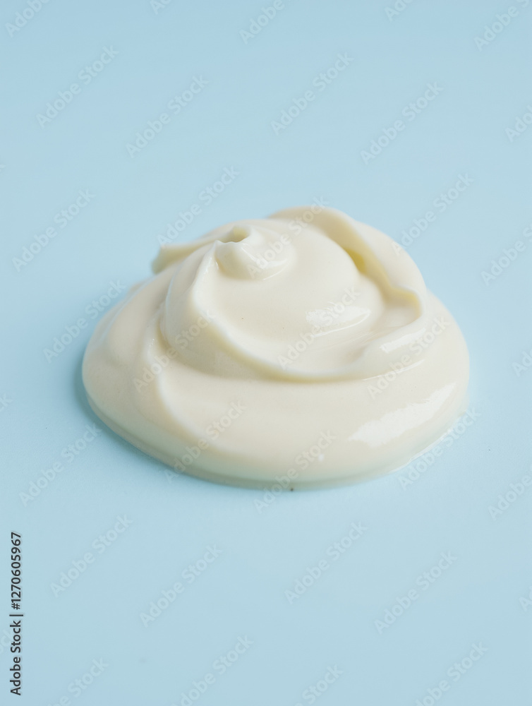 Swirl of smooth white cream on light blue surface Swirl of smooth white cream on light blue surface