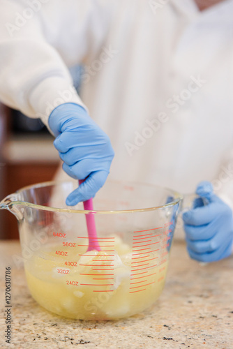 Billede på lærred Woman stirring lye and melted cocoa butter in a measuring cup