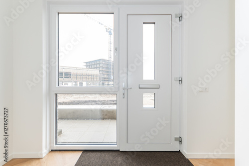 interior reception room of modern new build residential smart house looking through glass front door window at further development phase of project construction site building in scaffolding and crane