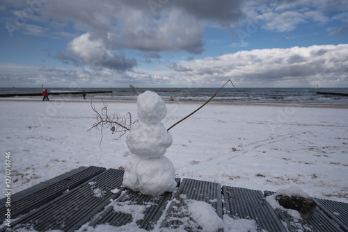 WINTER ON THE SEA COAST - Snwman and snow on the beach and people walking
