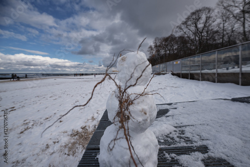 WINTER ON THE SEA COAST - Snwman and snow on the beach and people walking
