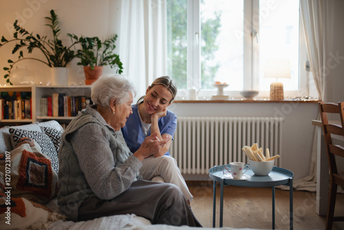 Tableau sur toile Caring healthcare worker visiting a senior patient at home, talking with her in living room